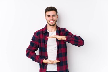 Beyaz arka planda poz veren beyaz bir genç iki eliyle bir şey tutuyor..