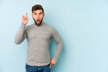 Mavi arka planda izole edilmiş beyaz bir adam ağzı açık bir şekilde üst tarafı işaret ediyor..