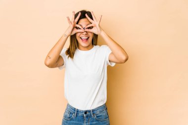 Bej arka planda izole edilmiş genç bir kadın heyecanlı..