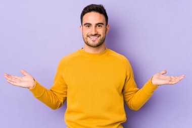 Mor arka planda izole genç beyaz adam kollarıyla ölçek yapar, mutlu ve kendinden emin hisseder..