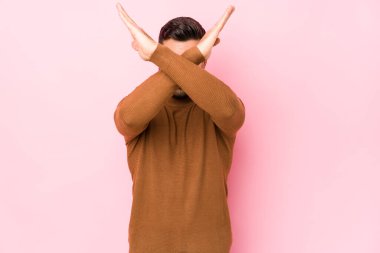 Pembe arka planda genç beyaz bir adam izole edilmiş iki kolu çapraz tutuyor, inkar kavramı..