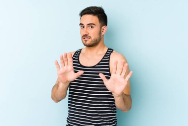 Mavi arka planda izole edilmiş genç beyaz adam tiksinti belirtisi gösteren birini reddediyor..