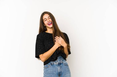 Beyaz arka planda soyutlanmış beyaz tenli genç bir kadın gülüyor, ellerini kalbe koyuyor, mutluluk kavramını koruyor..