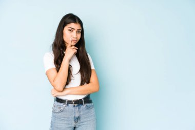 Mavi arka planda genç Hintli kadın bir strateji planlıyor, bir iş yolu düşünüyor..