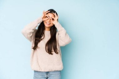 Mavi arka planda izole edilmiş genç Hintli kadın gözlerinde sorun olmadığını gösteriyor.