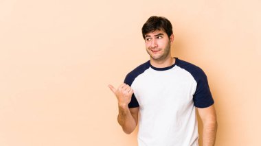 Bej arka planda izole edilmiş genç adam işaret parmağıyla fotokopi alanını göstererek şok oldu..