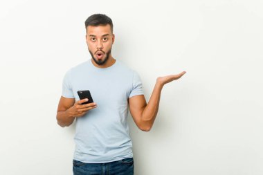 Elinde telefon tutan Asyalı genç melez bir adam avuç içinde fotokopi alanı tutmaktan etkilenmiş..