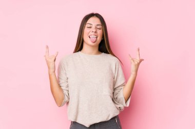 Genç beyaz kadın izole edilmiş poz veriyor. Parmaklarıyla kaya hareketi yapıyor.