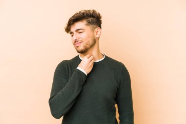 Bej arka planda izole edilmiş genç bir Arap adam virüs veya enfeksiyon yüzünden boğazında ağrı hissediyor..