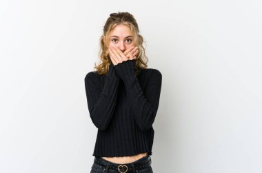 Beyaz arka plandaki genç beyaz kadın elleriyle ağzını kapatırken şok oldu..