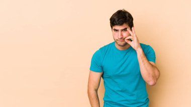 Bej arka planda izole edilmiş genç bir adam, parmakları dudaklarında bir sır saklıyor..