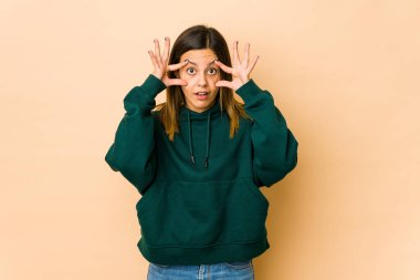 Bej arka planda izole edilmiş genç bir kadın bir başarı fırsatı bulmak için gözlerini açık tutuyor..