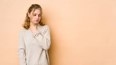 Bej arka planda izole edilmiş genç beyaz kadın virüs ya da enfeksiyon yüzünden boğazında ağrı hissediyor..