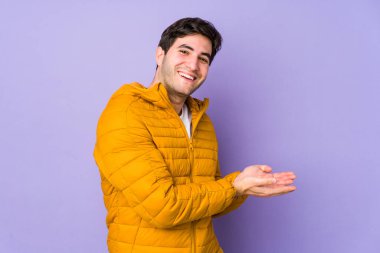 Mor arka planda izole edilmiş genç bir adam avucunun içinde bir kopya alanı tutuyor..