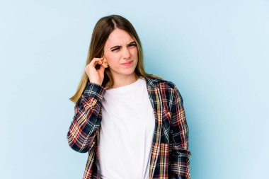 Genç beyaz kadın mavi arka planda izole edilmiş parmaklarıyla kulaklarını kapatıyor, gürültülü bir ortam yüzünden stresli ve çaresiz..