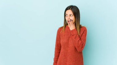 Mavi arka planda izole edilmiş genç bir kadın gördüğü bir şey yüzünden şok oluyor..