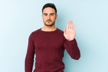 Mavi arka planda izole edilmiş genç beyaz adam elini uzatmış, dur işareti göstererek seni engelliyor..