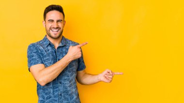 Sarı fırında izole edilmiş genç beyaz bir adam işaret parmağıyla fotokopi alanını işaret ederek heyecan ve arzusunu ifade ediyor..