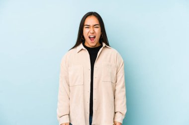 Mavi arka planda izole edilmiş genç bir kadın çok sinirli ve agresif çığlıklar atıyor..