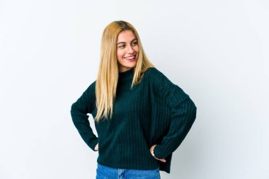 Beyaz arka planda izole edilmiş genç sarışın kadın mutlu bir şekilde gülüyor ve ellerini karnının üstünde tutarak eğleniyor..