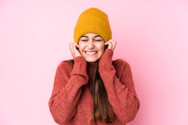 Kafkasyalı genç bir kadın yün bir şapka takıyor kulaklarını elleriyle kapatıyor..