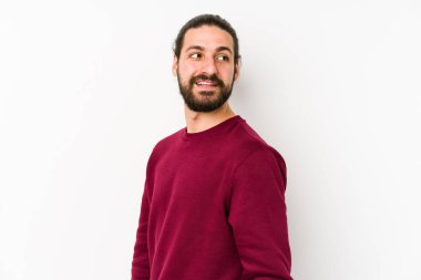 Genç, uzun saçlı, beyaz bir arka planda izole edilmiş, gülümseyen, neşeli ve keyifli bir adam..