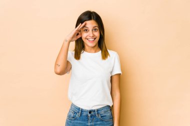 Bej arka planda izole edilmiş genç bir kadın yüksek sesle bağırıyor, gözleri açık ve elleri gergin tutuyor..