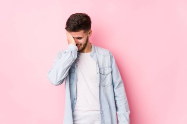 Beyaz arka planda poz veren beyaz tenli genç iş adamı bir şeyi unutuyor. Alnına avuç içi ve kapalı gözlerle vuruyor.