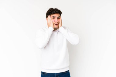 Genç adam beyaz arka planda izole edilmiş. Kulakları elleriyle kapatıyor. Gürültülü sesler duymamaya çalışıyor..