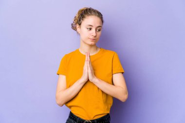 Mor arka planda genç beyaz bir kadın dua ediyor, bağlılık gösteriyor, dindar biri ilahi ilham arıyor..