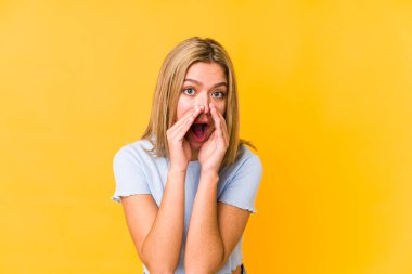 Sarışın, beyaz bir kadın sarı bir arka planda izole edilmiş ve heyecanlı bir şekilde bağırıyor..