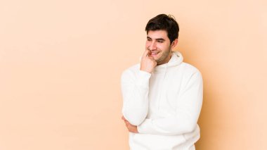 Bej arka planda izole edilmiş genç bir adam rahatlamış bir şeyin fotokopi odasına baktığını düşünüyor..