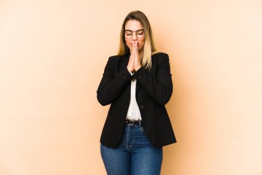 Orta yaşlı iş kadını, bej arka planda izole edilmiş, el ele tutuşmuş, ağzına yakın dua eden, kendinden emin..