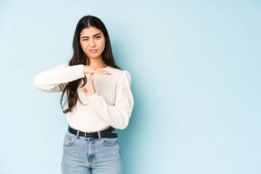 Mavi arka planda izole edilmiş genç Hintli kadın bir mola hareketi gösteriyor..