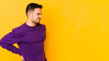 Genç beyaz adam sarı fırında izole edilmiş sırt ağrısı çekiyor..