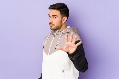 Mor arka planda izole genç beyaz adam yakın bir tehlike nedeniyle şoka uğruyor