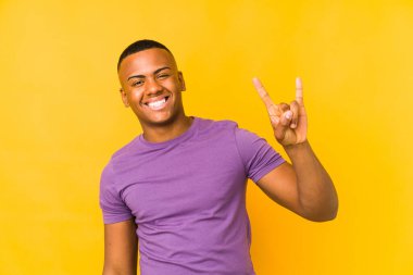 Sarı arka planda izole edilmiş genç latin adam boynuzları devrim konsepti olarak gösteriyor..