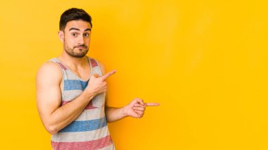 Sarı fırında izole edilmiş genç beyaz adam işaret parmağıyla fotokopi alanını işaret ederek şok oldu..