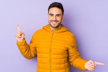 Mor arka planda izole edilmiş genç beyaz adam farklı kopya alanlarını gösteriyor, birini seçiyor, parmağıyla gösteriyor..