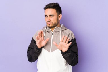 Mor arka planda izole edilmiş genç beyaz bir adam tiksinti belirtisi gösteren birini reddediyor..