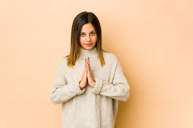 Bej arka planda izole edilmiş genç bir kadın. Dua ediyor, bağlılık gösteriyor. İlahi ilham arayan dindar bir insan..