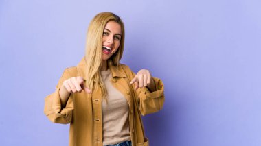 Mor arka planda soyutlanmış genç, sarışın bir kadın. Neşeli gülümsemeler öne bakıyor..