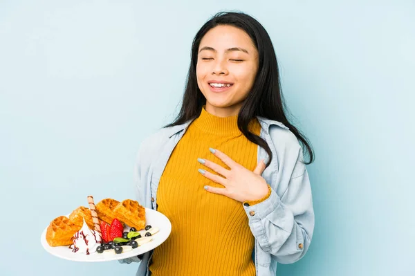 Joven Mujer China Sosteniendo Gofre Aislado Sobre Fondo Azul Sonriendo —  Fotos de Stock