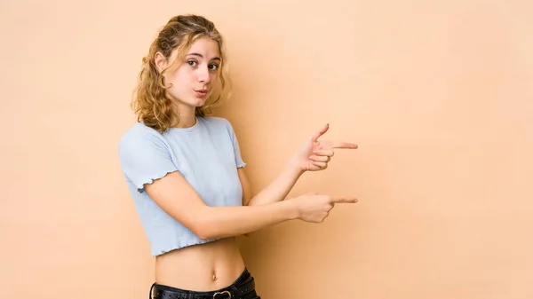 Young Caucasian Woman Isolated Beige Background Pointing Forefingers Copy Space — Stock Photo, Image