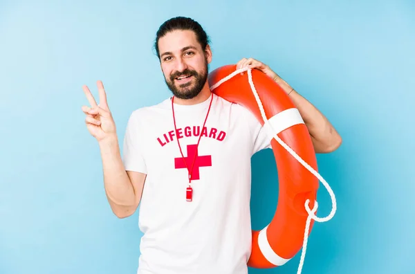 救助フロートを保持している若いライフガードの男は喜びと屈託のない指で平和のシンボルを示す — ストック写真
