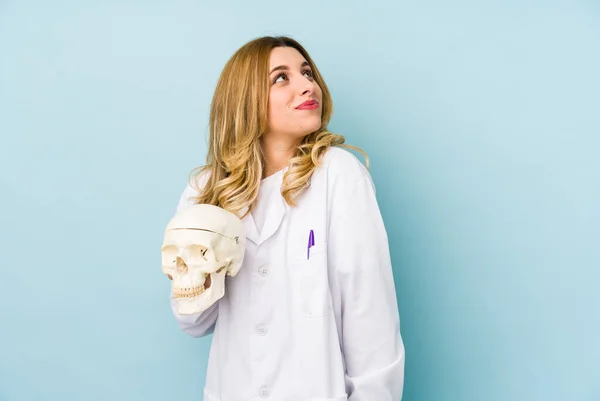 Young doctor woman holding a skull isolated dreaming of achieving goals and purposes