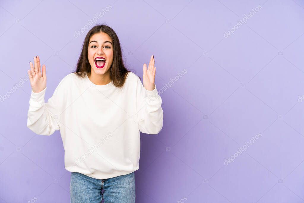 Young caucasian woman isolated on purple background receiving a pleasant surprise, excited and raising hands.