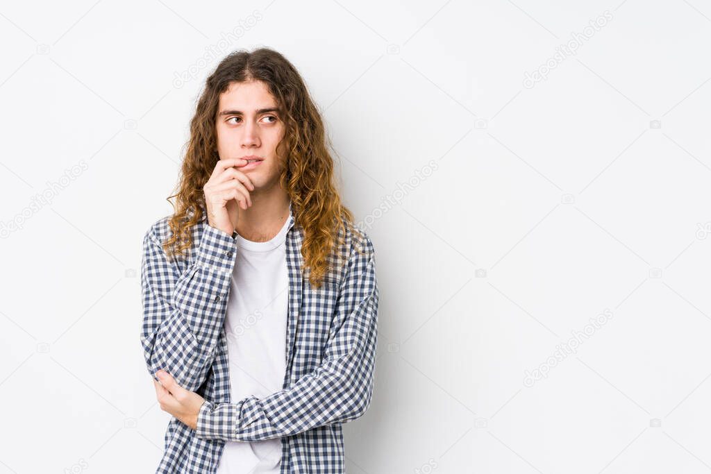 Young long hair man posing isolated relaxed thinking about something looking at a copy space.