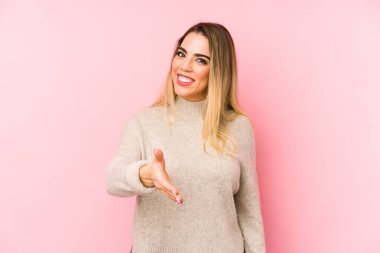 Orta yaşlı bir kadın izole edilmiş arka planda kameraya elini uzatarak selam veriyor..