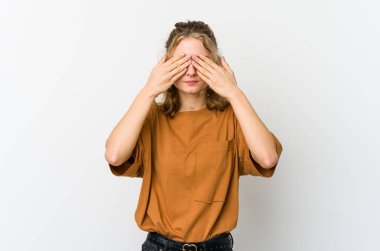 Beyaz arka plandaki genç beyaz kadın elleriyle gözlerini kapatmaktan korkuyor..